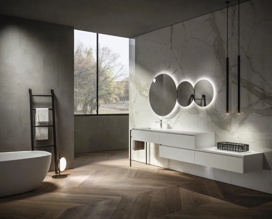 Visualizzazione di un ambiente bagno con vasca freestanding, mobile sospeso e specchi tondi retroilluminati