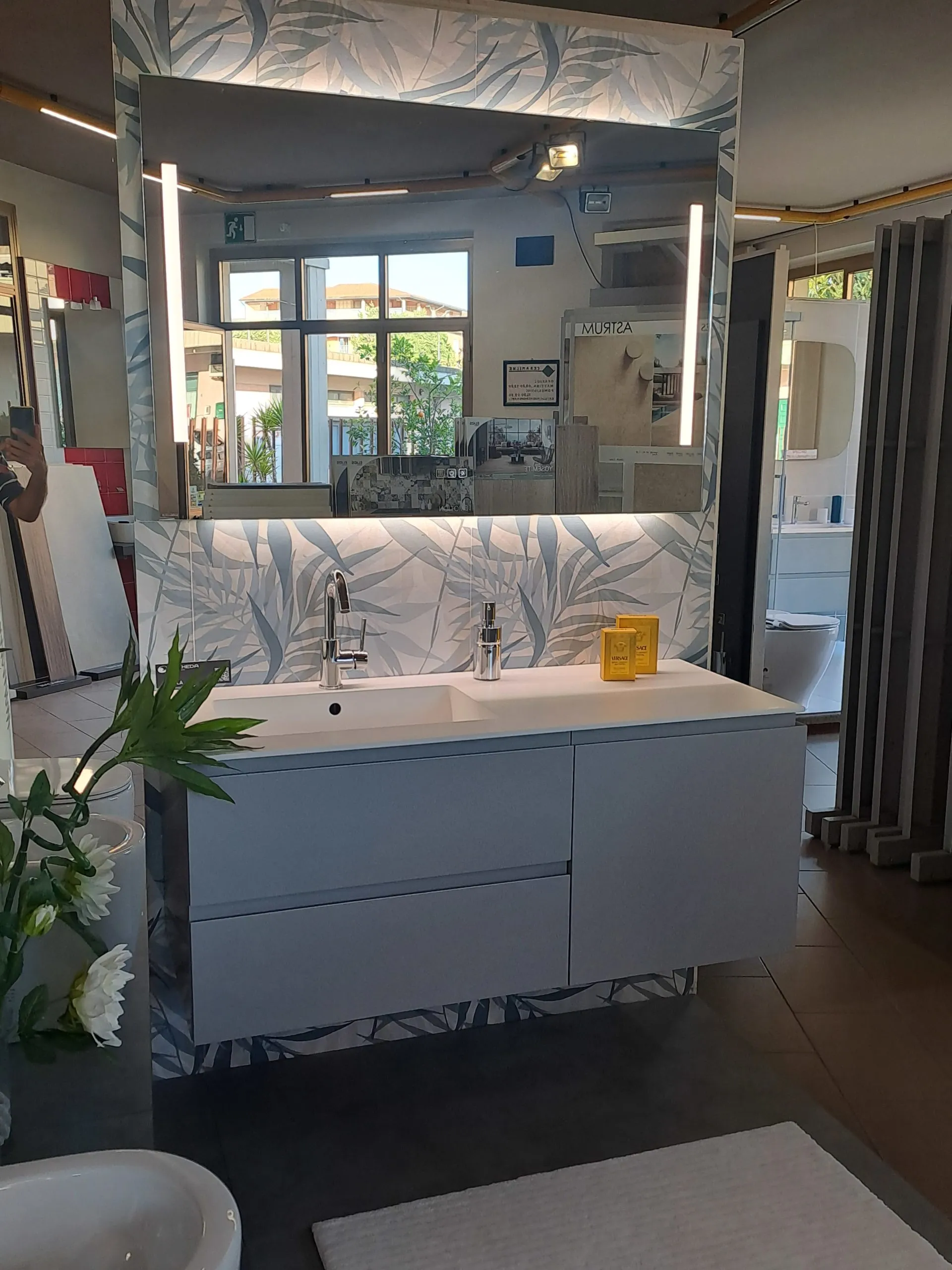 Composizione bagno con mobile grigio e specchio retroilluminato esposta nello showroom SL Ceramiche