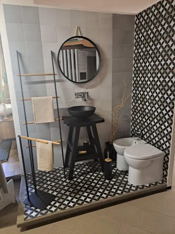 Angolo bagno con pavimento geometrico bianco e nero, lavabo da appoggio su struttura metallica nera