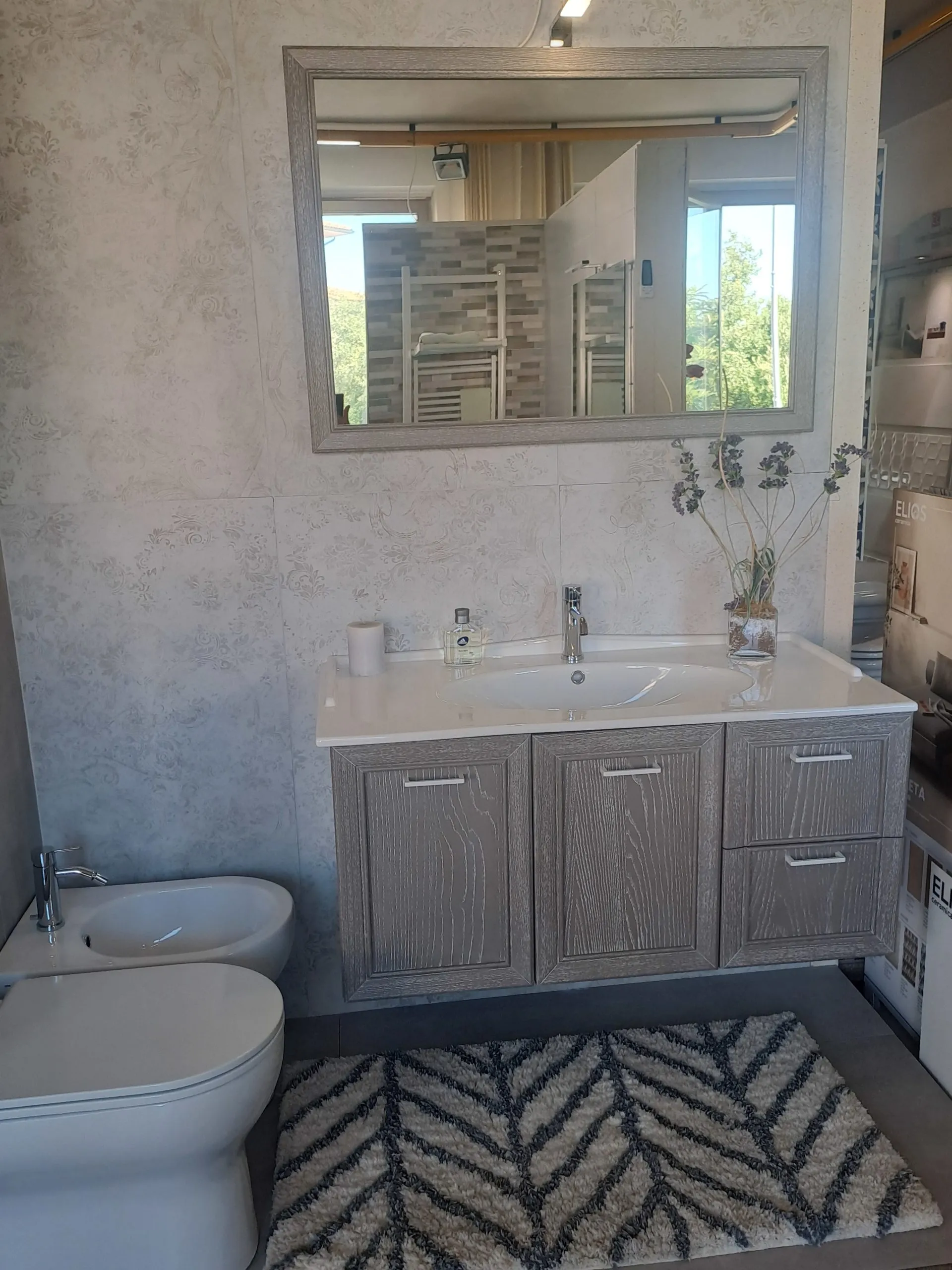Mobile bagno in legno grigio decapato con specchio coordinato e parete effetto pietra
