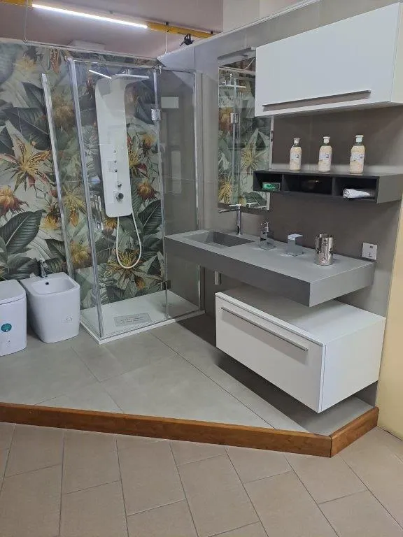 Bagno con rivestimento a soggetto botanico, mobile bianco e mensole a giorno