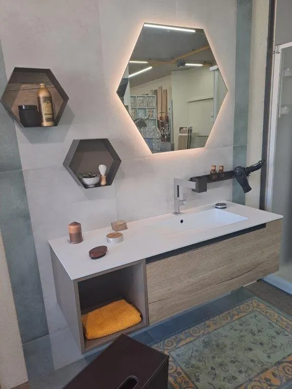 Bagno con specchio esagonale retroilluminato, mensole esagonali e mobile effetto legno
