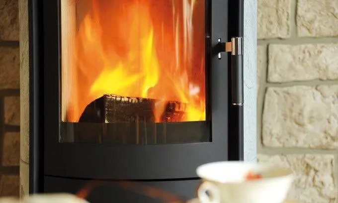 Stufa con fiamma viva accanto a una parete in pietra