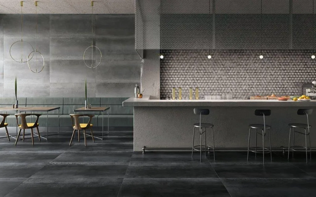 Ambiente living con cucina a isola, pavimento e rivestimento in gres effetto metallo scuro